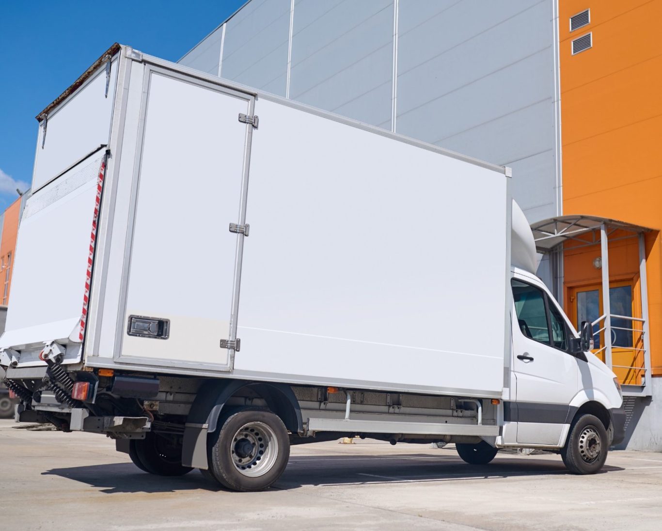 Transporter für eine Messie Entrümpelung in Berlin Ein weißer Lieferwagen parkt vor einem großen Gebäude mit orangefarbener Fassade.